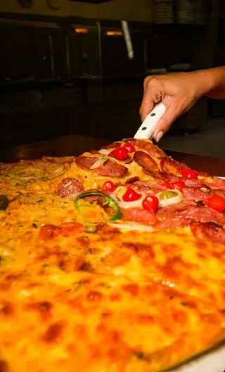 Pizza sendo cortada nos bastidores do Ki-Sabor
